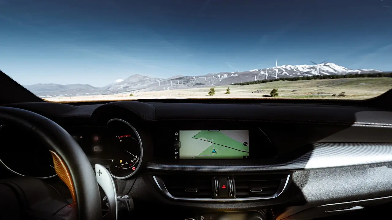A modern car dashboard with the instrument cluster and navigation screen, mountains through the windscreen.
