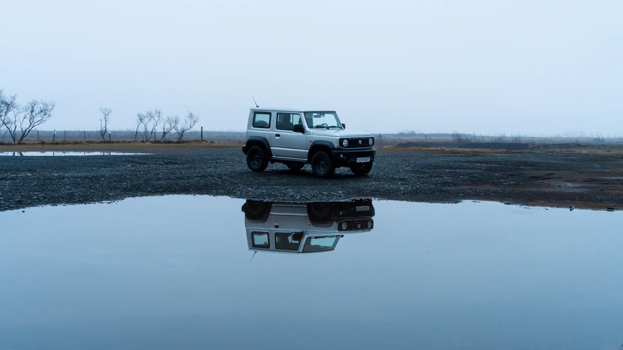 Silver suv reflected in a calm puddle