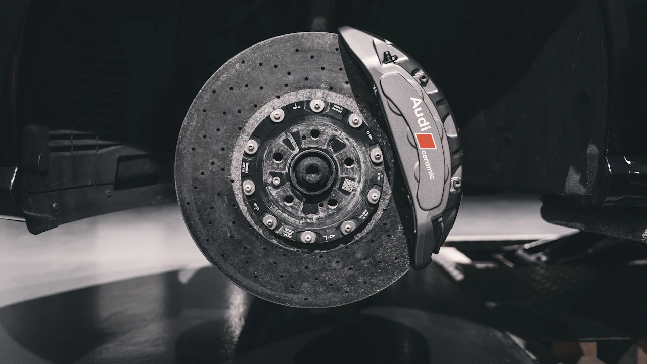A car's drilled brake rotor and caliper, seen at the wheel