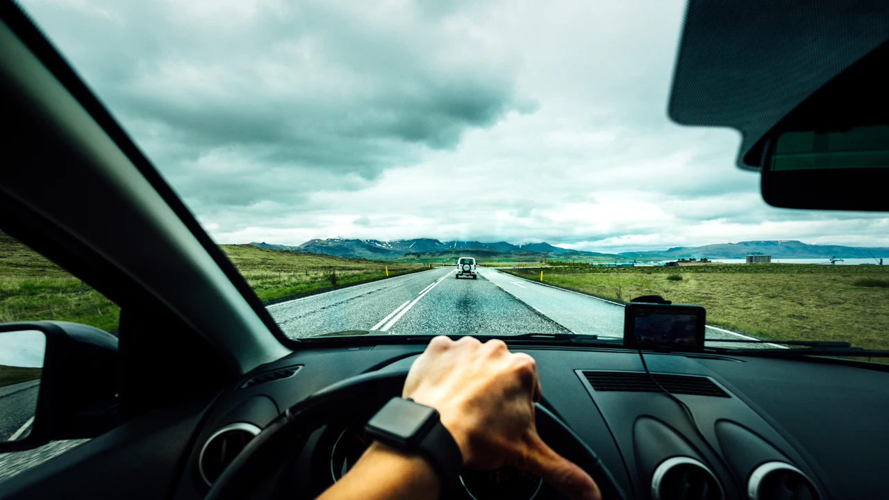 A driver's hands on the steering wheel on an open road