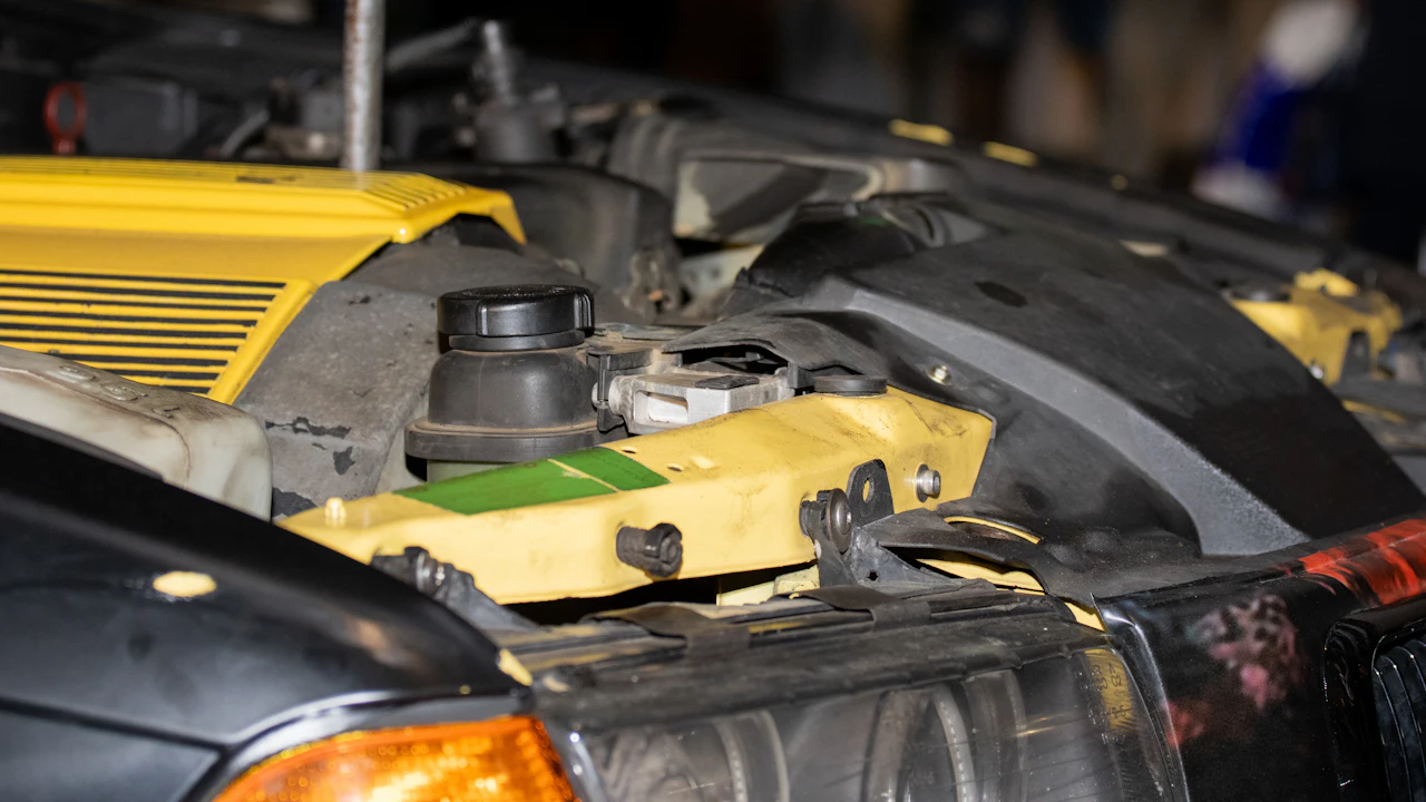 The front of a car's engine bay with the hood up, showing the radiator support area and a fluid cap