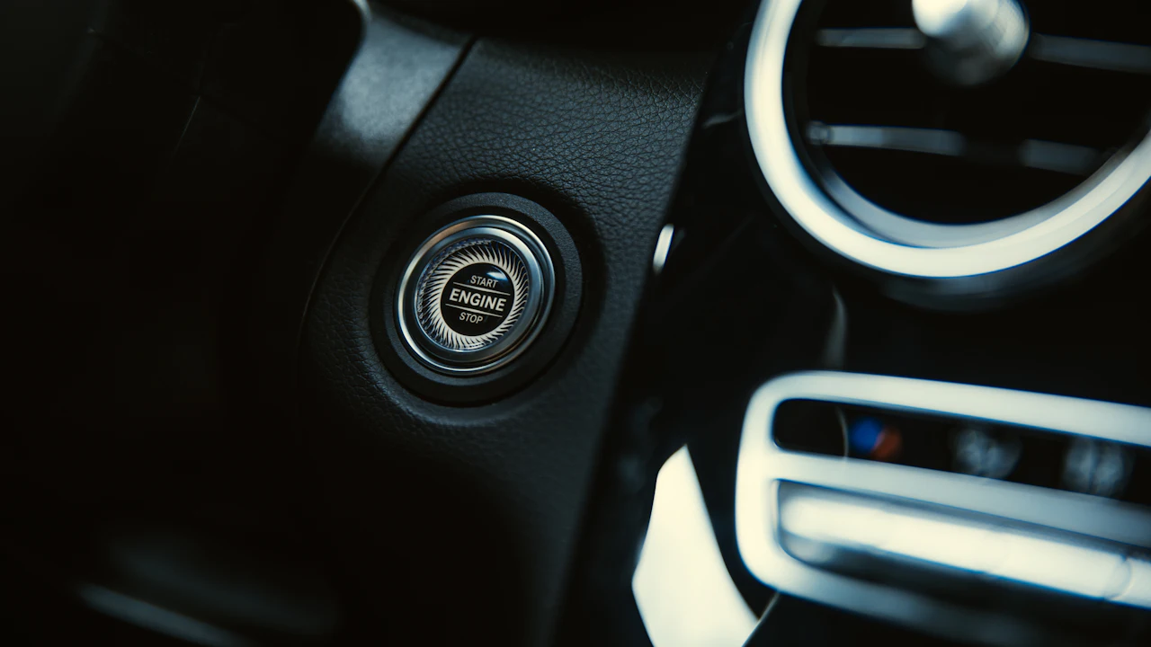A car's engine start/stop button on the dashboard, an air vent to the right