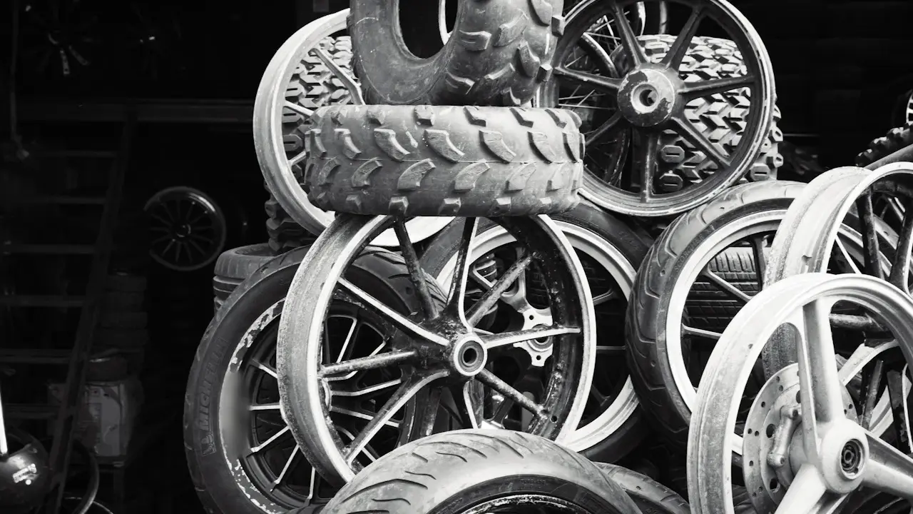 A pile of used tires and spoked wheels in a dark shop, in black and white.
