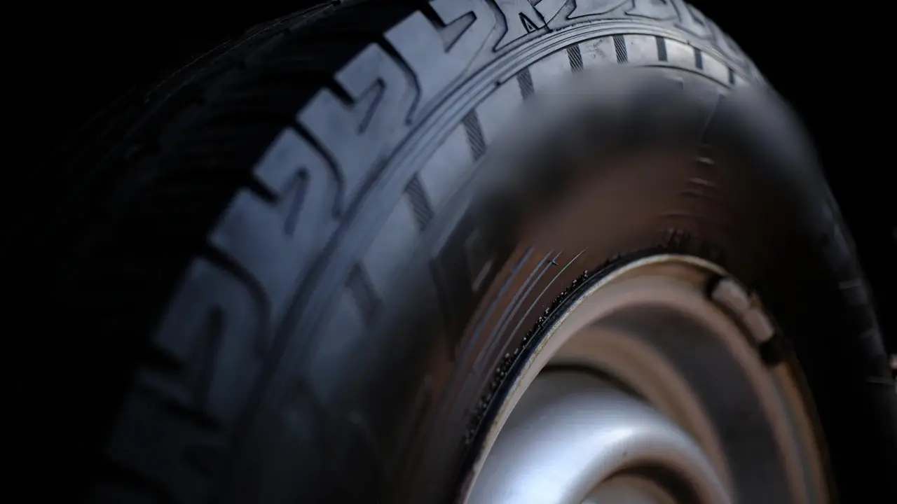 Close view of a mounted tire's tread blocks and sidewall above a steel wheel.