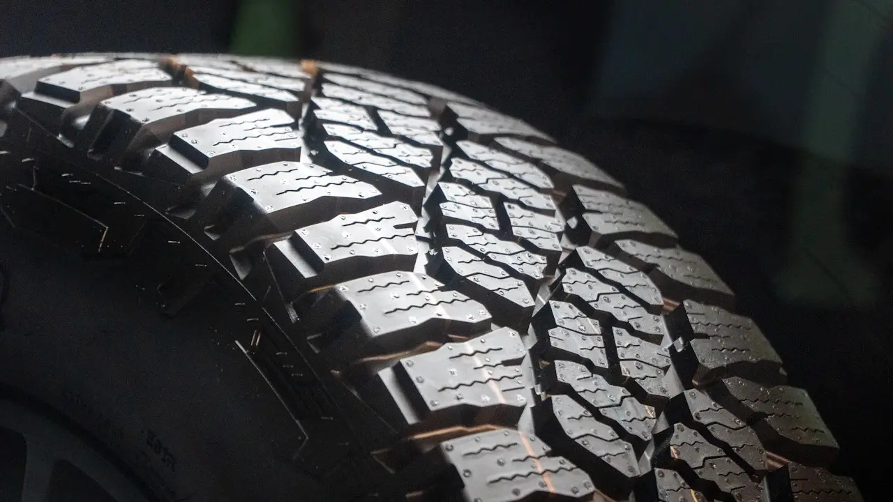 Close view of a deep all-terrain tire tread and the dark sidewall beside it.