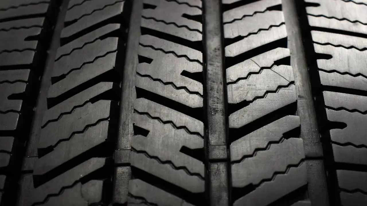 Close view of a tire's tread blocks and straight grooves.