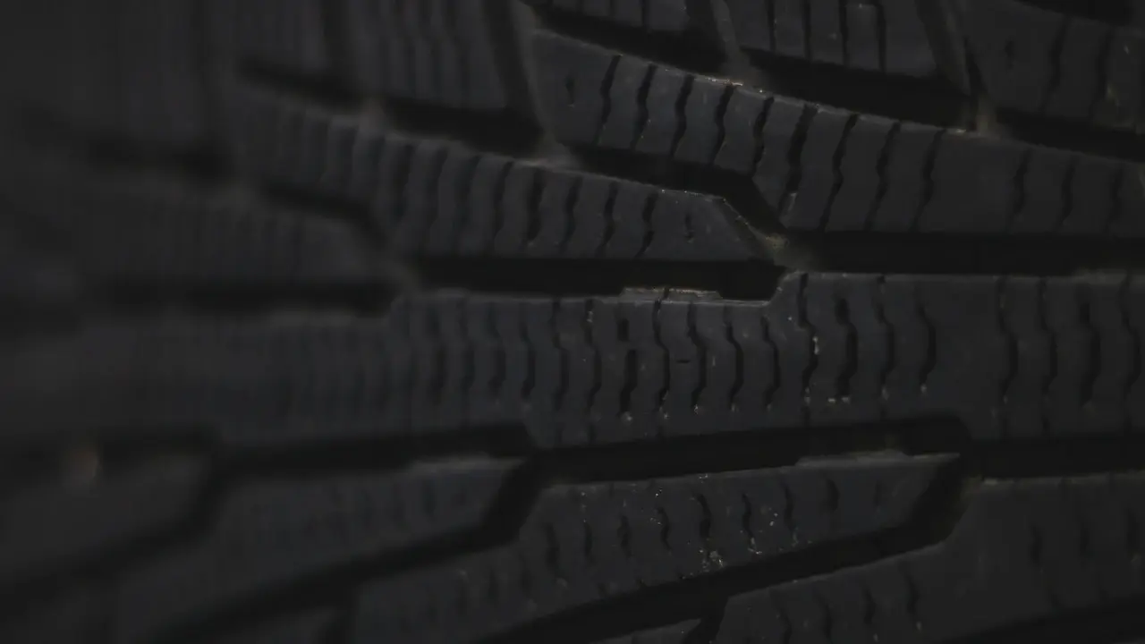 Close-up of the tread blocks and grooves of a car tire.