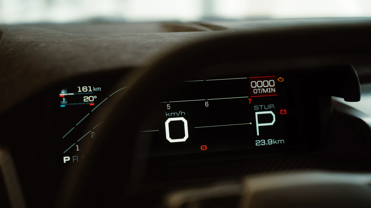 A digital instrument cluster behind a steering wheel showing zero speed, the letter P for park, a trip distance and a range figure