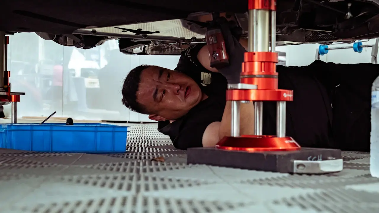 A mechanic working under a car raised on a lift.