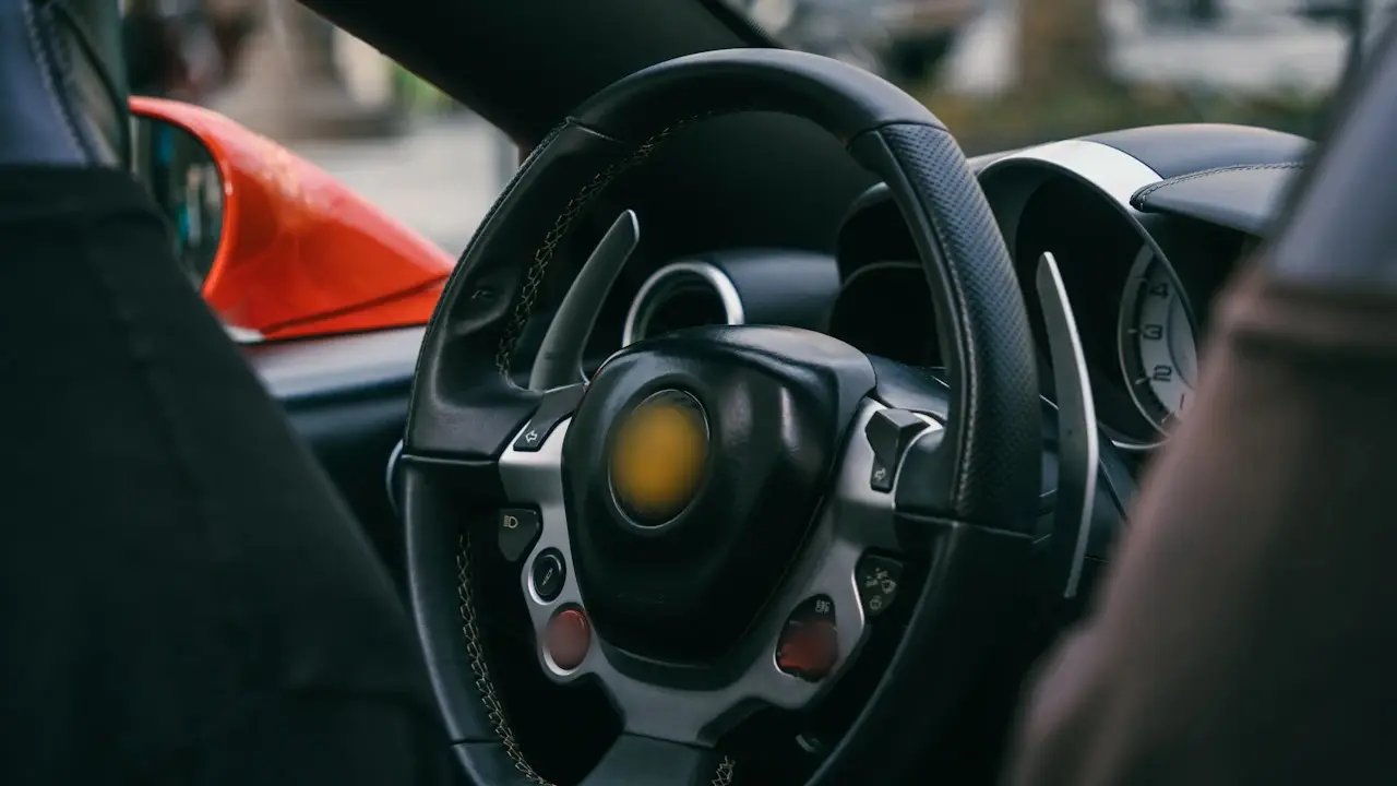A sports car's steering wheel with paddle shifters and buttons, seen from the driver's seat.
