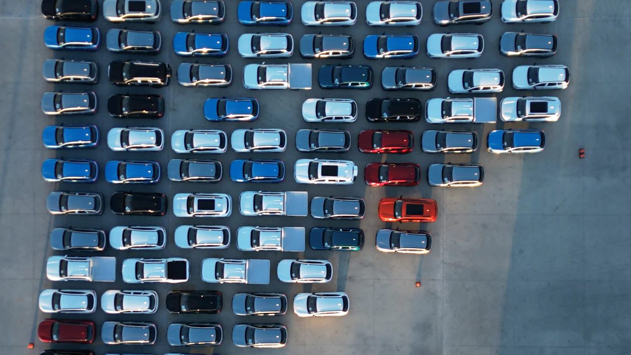 An aerial view of rows of new cars parked on a dealership lot