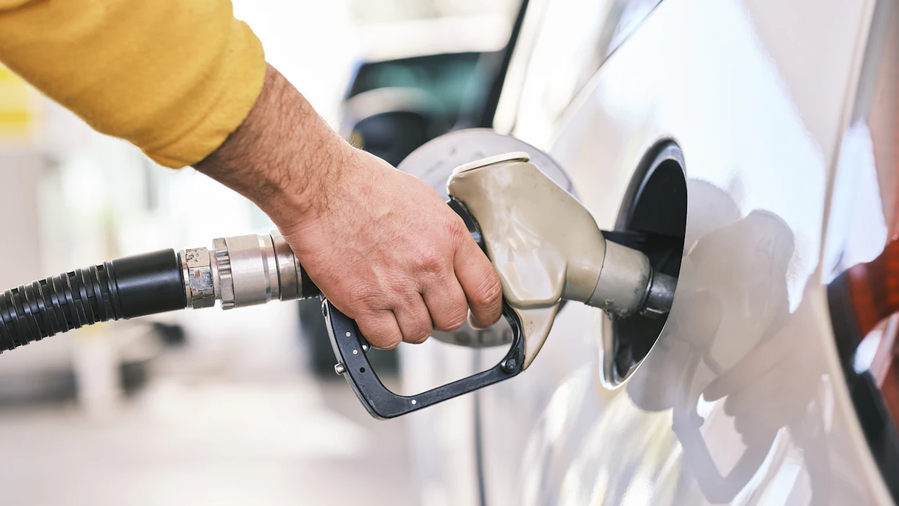 A person refuelling a white car at a filling station