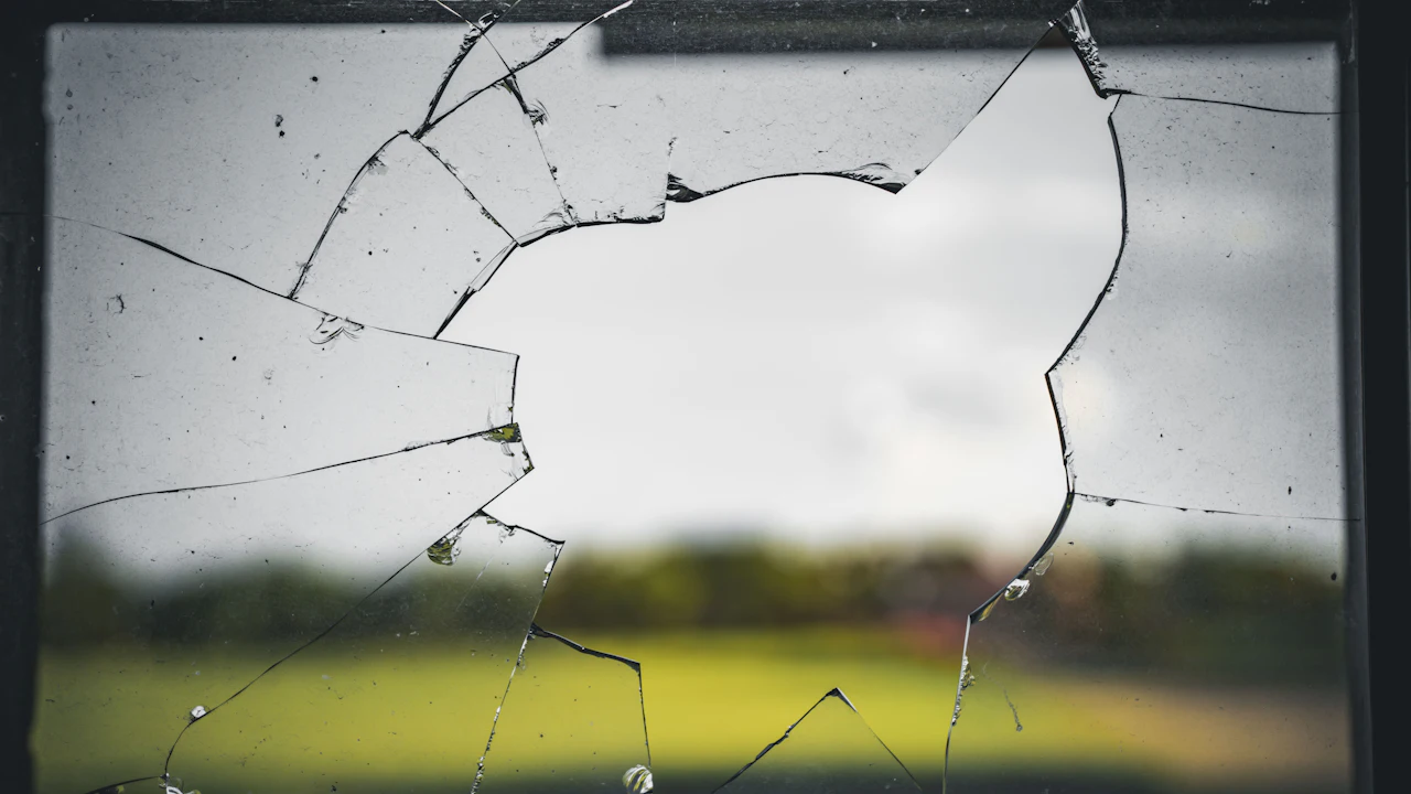 A cracked pane of glass photographed against a green field beyond